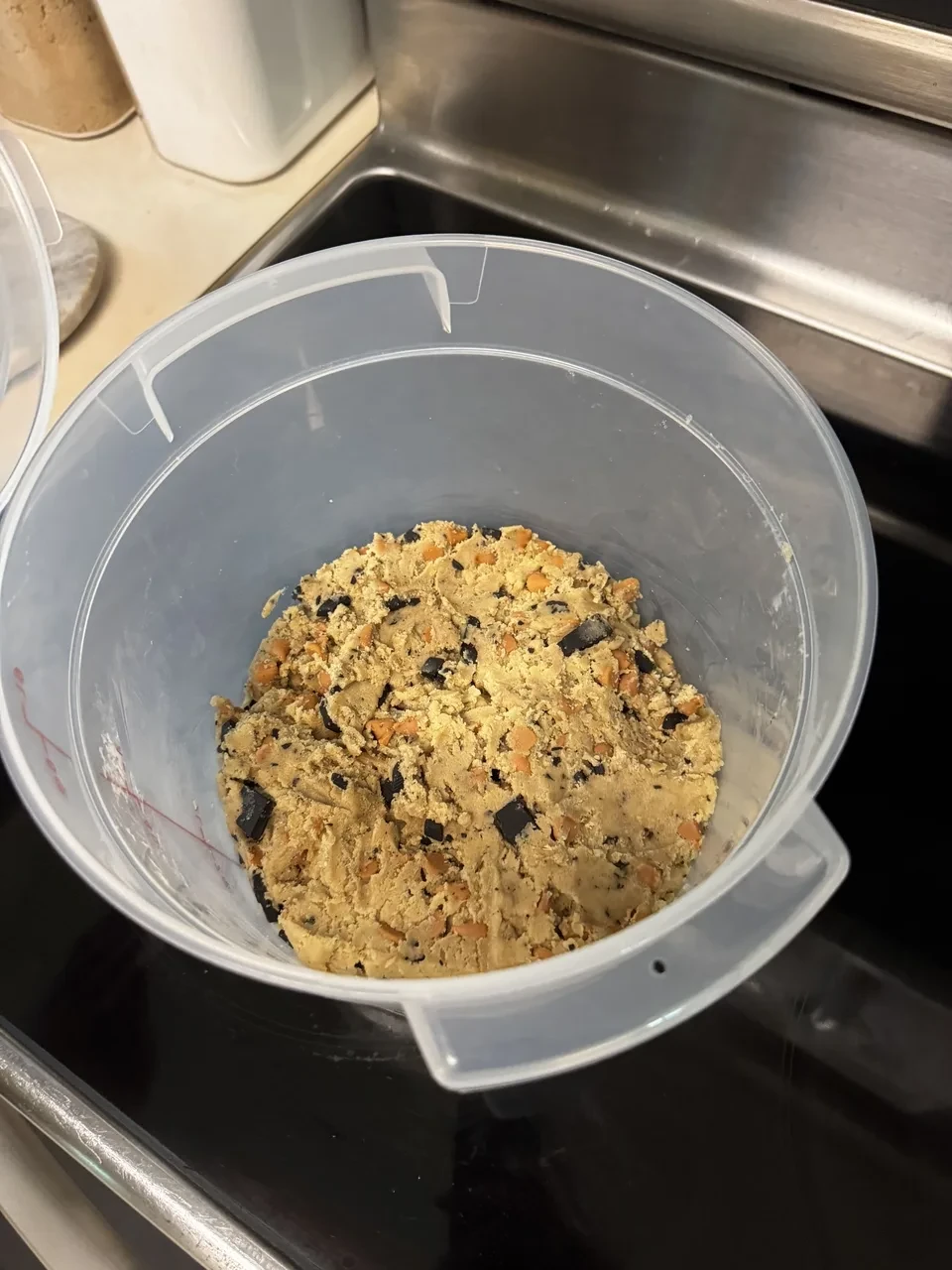 a plastic food-safe container partially filled with chocolate-and-butterscotch-chip cookie dough