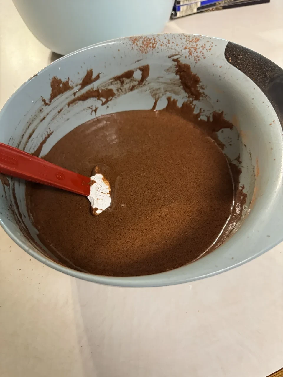 a mixing bowl containing darker brown batter