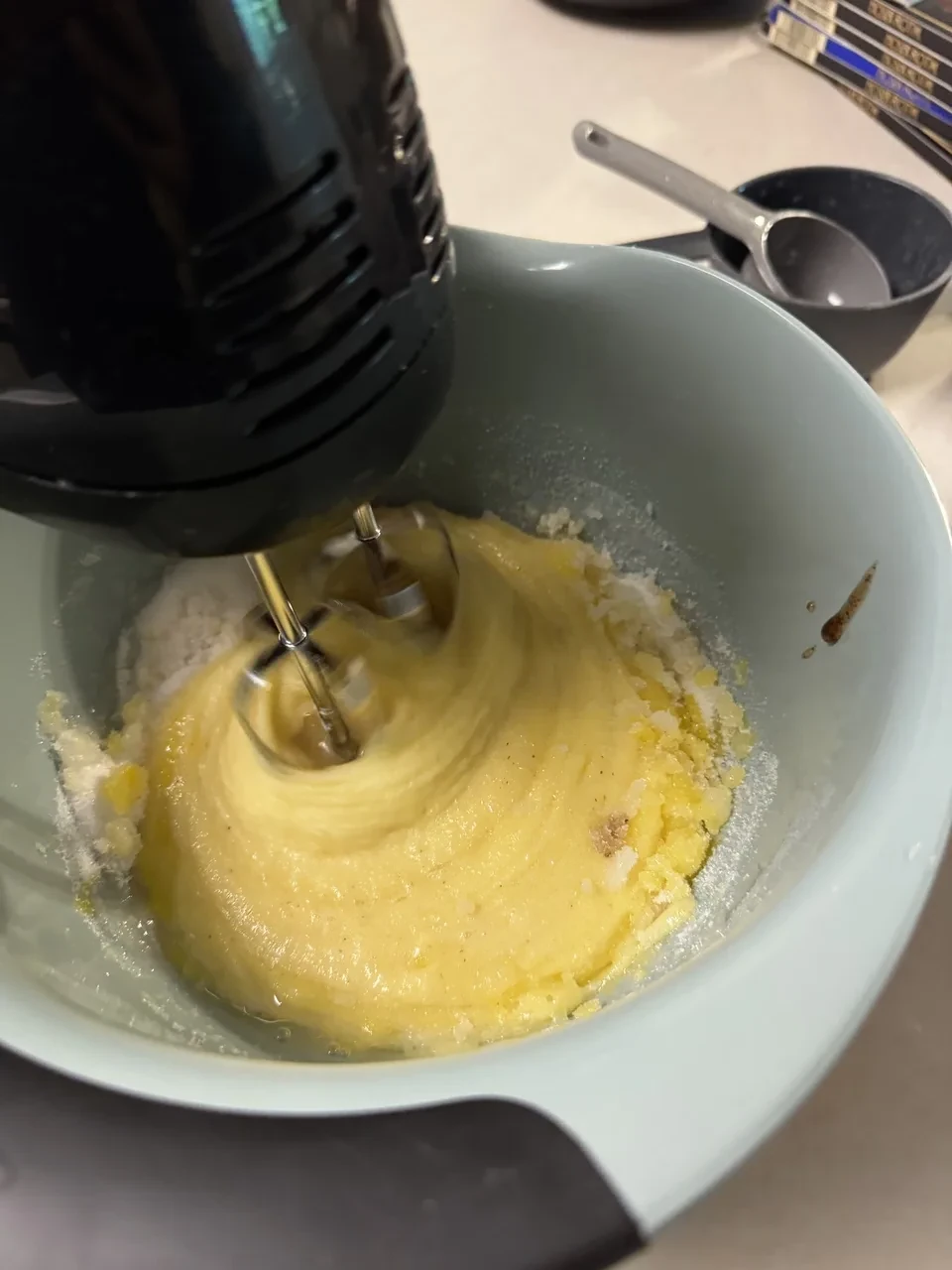 a mixing bowl with eggs, vanilla paste, and sugar being blended with a hand mixer
