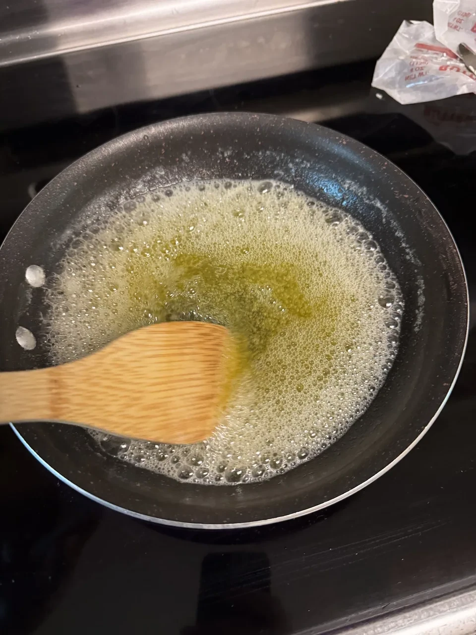 fully-melted and darkened butter being stirred with a wooden spoon in a saucepan