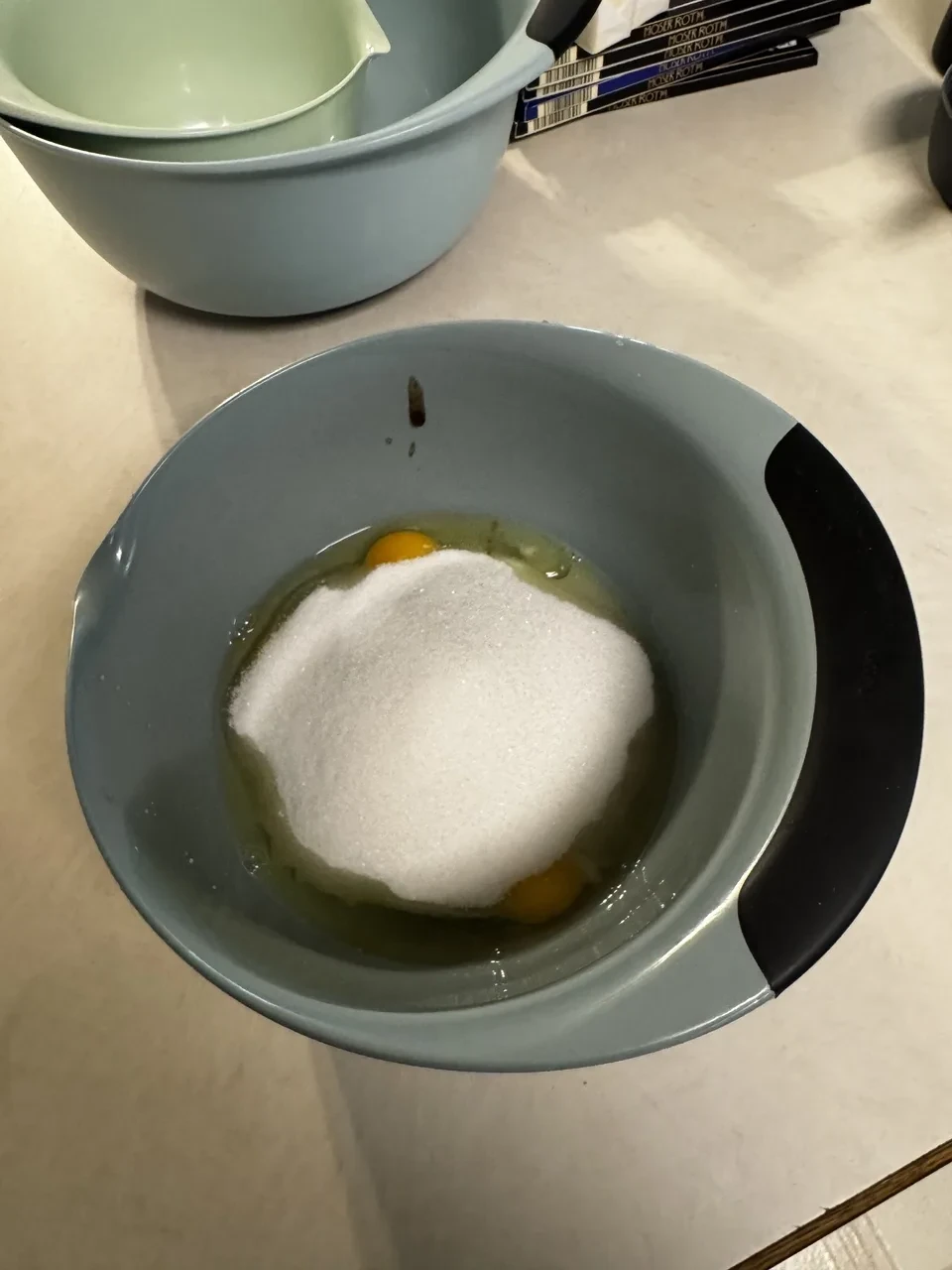 a mixing bowl containing four eggs, vanilla paste, and sugar