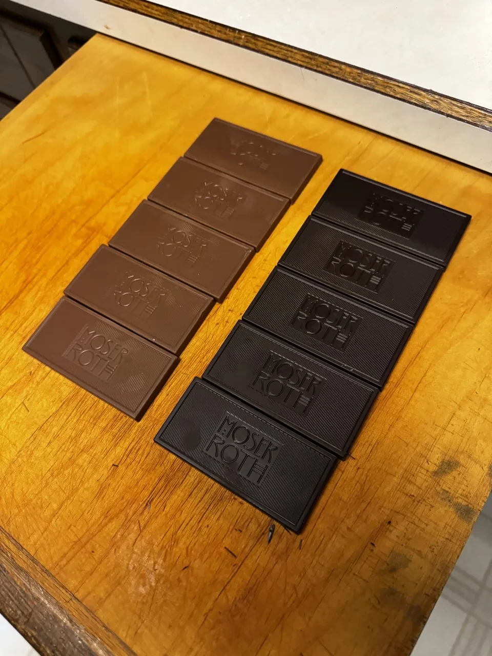 five bars of milk chocolate and five bars of dark chocolate on a wooden cutting board