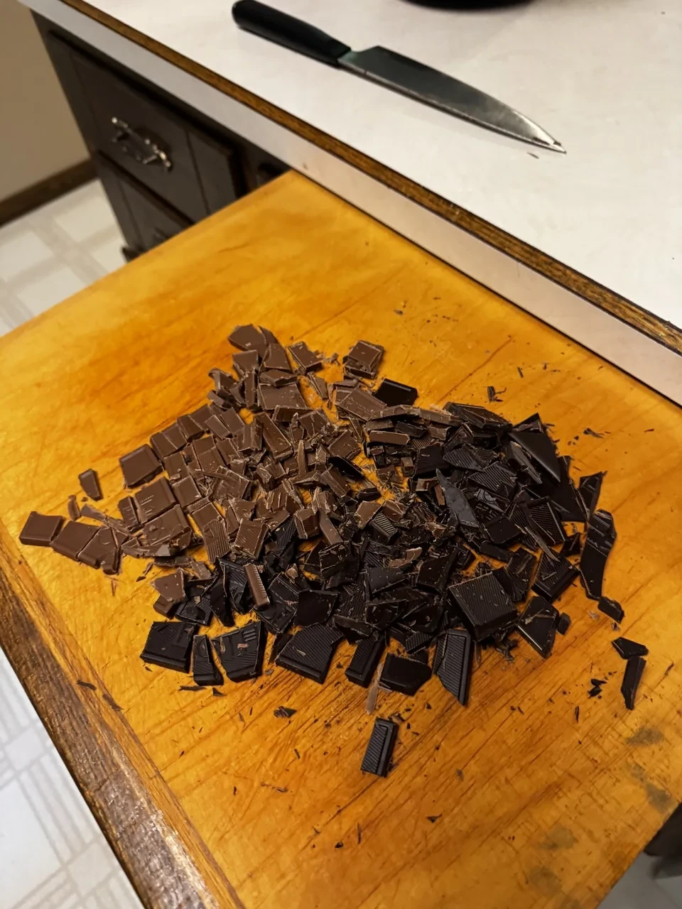 a pile of milk and dark chocolate chunks on a wooden cutting board