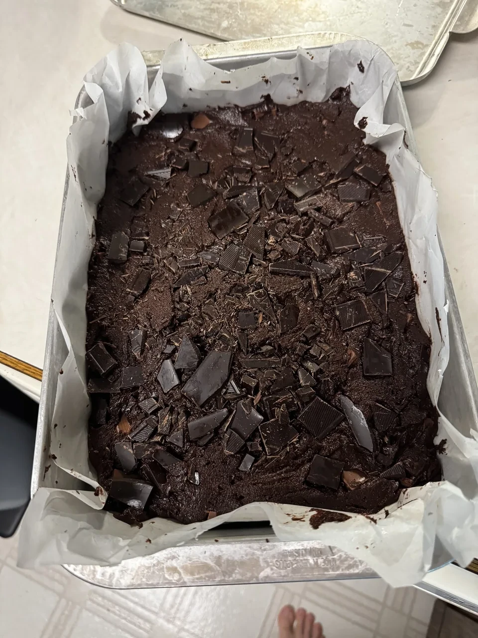 a 9 by 13 inch baking pan containing chocolate brownie batter and liberally sprinkled with chocolate drunks